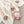 Cream knit blanket with pink crochet flowers and a smiling pink plush flower toy.