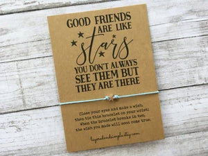 Brown card with a friendship quote, star accents, and a light blue string bracelet attached.