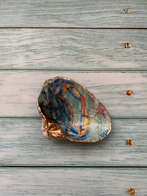 Handmade painted shells featuring summer crab designs, crafted by Serenity Shells, displayed on a neutral background.