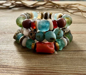 Multicolored beaded bracelets with blue, green, red, and gold beads on a wooden surface.