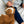 Child in blue sweater holds brown lion plush toy with curly texture.