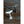 Two whale tail hooks, one white and one black, on a rustic, weathered wooden surface.
