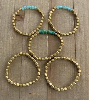 Turquoise glass and brass bracelet set featuring handmade Nellie Pratt Artisan Jewelry with vibrant beads and intricate metalwork.