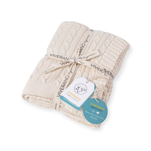 Cream-colored cable knit blanket tied with branded ribbon and tags, showcasing "Viverano Organics."