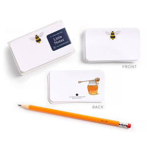 White note cards with bee and honey jar illustrations, an orange pencil, and packaging.