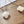 Gold earrings with white clover-shaped stones on a wooden surface.