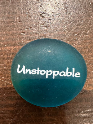 Imprinted glass word stones from SHOPGIVECOURAGE displayed in a bowl, featuring inspirational words on smooth, polished stones.