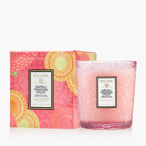 Pink glass candle with floral pattern, beside a colorful floral box labeled "Napali Passion Fruit."