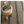 Round wooden stool with books and vase on checkered brown and black rug.