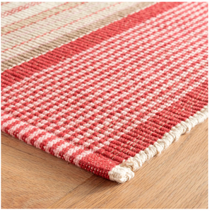 Red and beige checkered rug with a woven texture on a wooden floor.