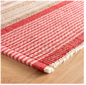 Red and beige checkered rug with a woven texture on a wooden floor.