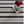 Black and white striped rug with stacked books and a vase of red flowers.