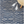 Blue geometric patterned rug with white sneakers and a woven stool on a wooden leg.