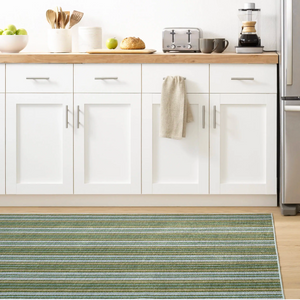 Modern kitchen with white cabinets, wooden countertop, green striped rug, and stainless steel appliances.