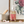 Clear soap bottle with pink text, on a shelf with rose petals, brush, and floral artwork.
