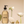 Clear soap bottle with pump, surrounded by white flowers, green grapes, and an olive on a beige background.