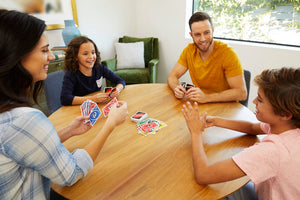 Toysmith UNO game with colorful cards fanned out, featuring the classic Mattel Games logo on the box in the background.