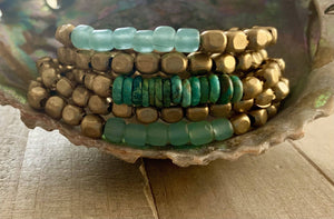 Turquoise glass and brass bracelet set by Nellie Pratt Artisan Jewelry with multiple bangles and intricate bead details.
