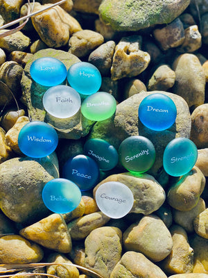 Sea stones with engraved glass words displayed in a bowl, featuring 60 imprinted glass word stones from SHOPGIVECOURAGE.