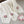 Cream knitted blanket with pink flower patterns, next to a smiling pink flower plush on gray tile.