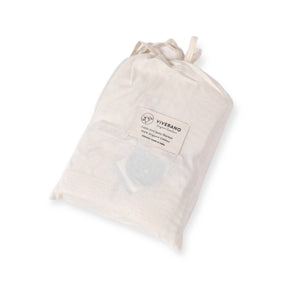 Cream-colored drawstring bag with a logo and text label, containing a folded blanket inside.