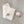 Cream knitted blanket with pink flower detail, next to a smiling plush pink flower toy on gray surface.