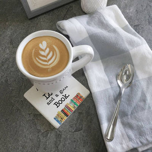 Coaster featuring "All You Need Is Love and a Good Book" text from Tipsy Coasters & Gifts, with a decorative design on a wooden surface.