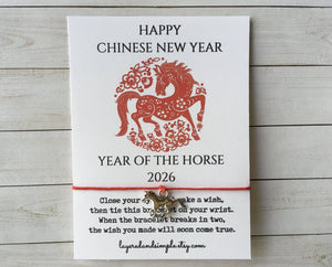 White card with a red horse design, text about Year of the Horse 2026, and a red string bracelet.