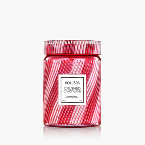 Red glass candle jar with diagonal grooves, white label, and "Voluspa Crushed Candy Cane" text.