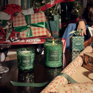 Green candles on a table, holiday gifts, wrapping paper, and a vintage red wagon in the background.