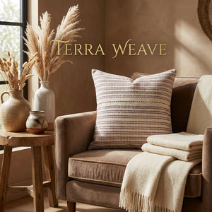 Cozy living room with a brown sofa, patterned cushion, cream throw, and vases of pampas grass.