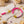 Colorful bracelets with pink and pastel beads, yellow smiley faces, and pearl hearts on wood.