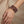 Hand with mauve beaded bracelets and bronze accents on beige background.