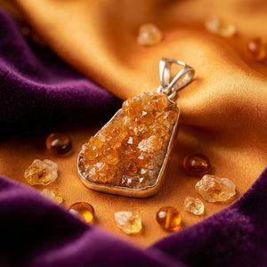 Pendant with amber crystals on golden and purple fabric, surrounded by small amber stones.