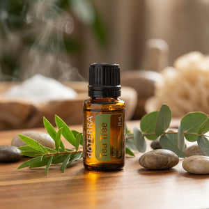 Amber essential oil bottle on wooden table with green leaves and smooth stones; steam in background.