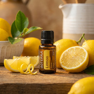 Amber bottle of lemon essential oil with fresh lemons on a wooden surface.