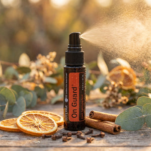 Spray bottle of sanitizer with citrus slices, cinnamon sticks, and leaves on a wooden surface.