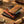 Stacked leather wallets on wooden surface, surrounded by coins, a compass, and a rolled map.