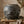 A weathered, dark ceramic pot on a wooden table with dried leaves and branches around it.