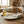 Rustic kitchen scene with a wooden table, glass oil bottle, salt bowl, and textured plate with cloth.