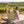 Wicker basket with baguettes, wine, cheese, and grapes on a picnic table in a vineyard setting.