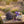 Bundle of lavender with purple bow, essential oil bottles, and mortar on rustic table in field.