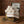 Rolled white towels with colorful stripes in a vintage metal box, on a wooden table. Brick wall backdrop.