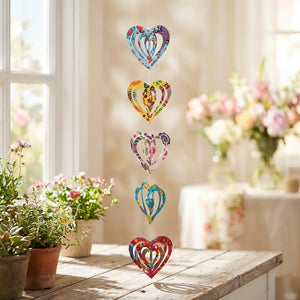 Colorful heart-shaped paper garland hanging in a sunlit room with flowers and wooden table.