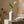 White calla lily in a sleek white vase on a stone surface, with beige textured background.