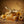 Golden bee sculpture on honeycomb with flowers on a wooden table, warm brown background.