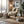 Cozy room with fur-draped chair, knit blanket, plants, and a lamp by a snowy window.