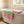 Pink and green striped towels on a white bathtub with a window and white tiled wall.