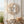 Seashell wreath on white door, with a wooden bench holding folded linens and a basket of shells.