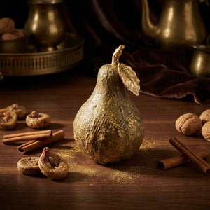 Golden pear centerpiece, with figs, cinnamon sticks, and walnuts on a wooden table.